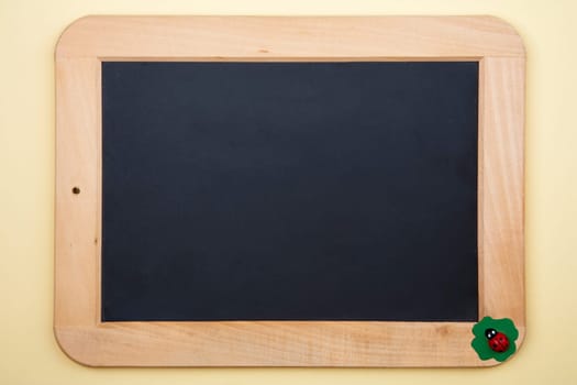 Decorative Blackboard with little wooden junic beetle on yellow background