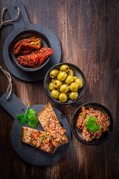 Tapenade - delicious olive paste from France with ingredients and crostini. Top view.