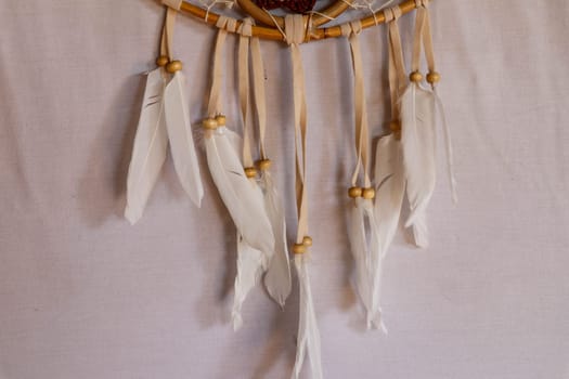 Closeup of white dream catcher a small white hoop decorated with feathers and beads.