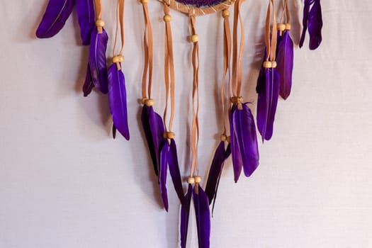 Closeup modern dreamcatcher with purple feathers. White background.