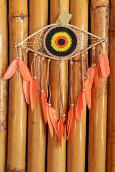 divine eye of providence dreamcatcher with colored feathers on a wodden background.