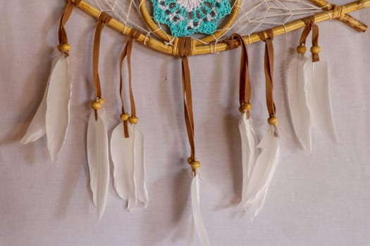 Closeup of white dream catcher a small white hoop decorated with feathers and beads.
