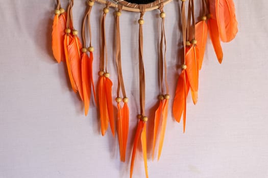 Dream catcher, decorated with white feathers and wooden beads, on a wooden surface. Dream catcher with wooden circle. Knitted Native American amulet with the symbol of Yin Yang on a wodden background.