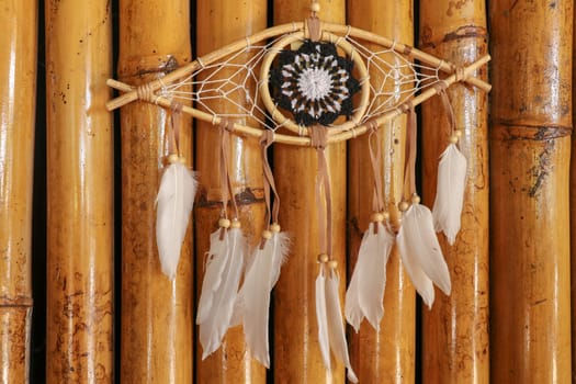 god eye of providence dreamcatcher with white feathers on a wodden background.