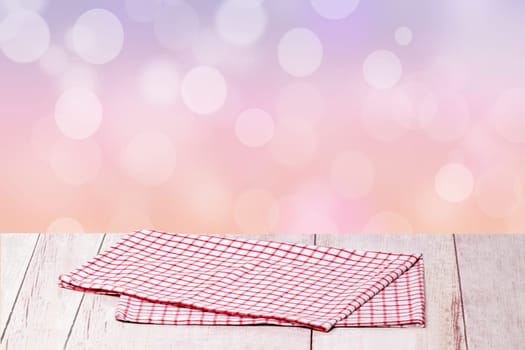 Empty table product. Closeup of a empty red checkered tablecloth or napkin on a rustic bright table over abstract pastel pink background. Template for your food and product display montage.