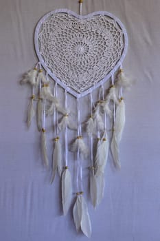 Dream catcher shaped heart with beige peacock feathers in the interior.