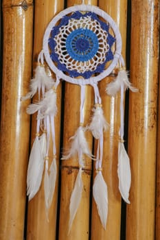 Blue Dreamcatcher with feathers and beads isolated on a wodden background.