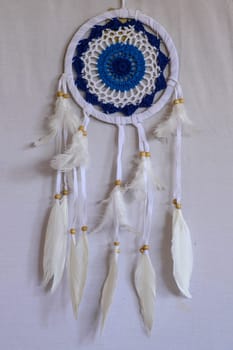 Blue Dreamcatcher with feathers and beads isolated on a white background.
