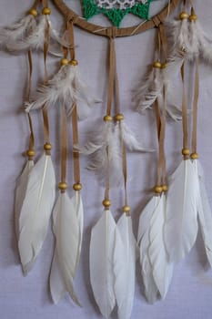 Closeup of white dream catcher a small white hoop decorated with feathers and beads.