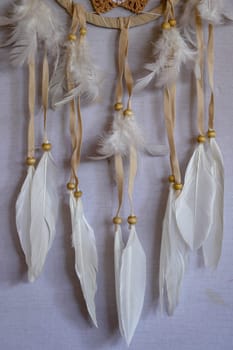 Closeup of white dream catcher a small white hoop decorated with feathers and beads.