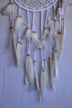 Closeup of white dream catcher a small white hoop decorated with feathers and beads.