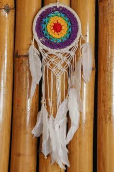 Beautiful multicolored handmade dreamcatcher on natural bamboo background.