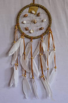 sea shell decoration. dream catcher. Handmade pink native american dream catcher on background of rocks and lake. Tribal elements, feathers, shells, lace