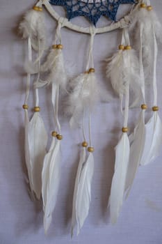 Closeup of white dream catcher a small white hoop decorated with feathers and beads.