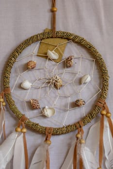 sea shell decoration. dream catcher. Handmade pink native american dream catcher on background of rocks and lake. Tribal elements, feathers, shells, lace