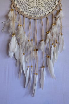 Closeup of white dream catcher a small white hoop decorated with feathers and beads.