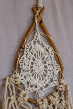 Beige crochet doily dream catcher close up on gray textured background. Texture of concrete, white background.