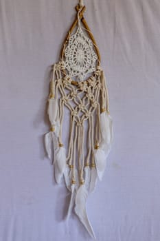 Beige crochet doily dream catcher close up on gray textured background. Texture of concrete, white background.