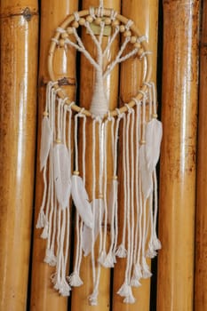 White dreamcatcher - Indian amulet that protects the sleeper from evil spirits and diseases.. The tree - symbol of life. Dream catcher on bamboo background.