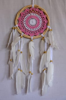 Pink ash crochet doily dream catcher close up on dark gray textured background. Texture of concrete, copy space for text. White background.