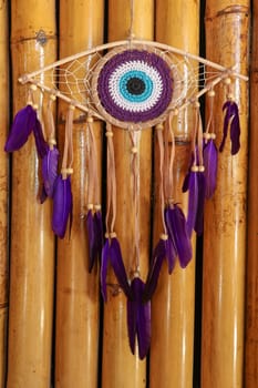 divine eye of providence dreamcatcher with colored feathers on a wodden background.