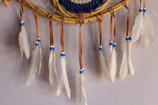 Closeup of white dream catcher a small white hoop decorated with feathers and beads.