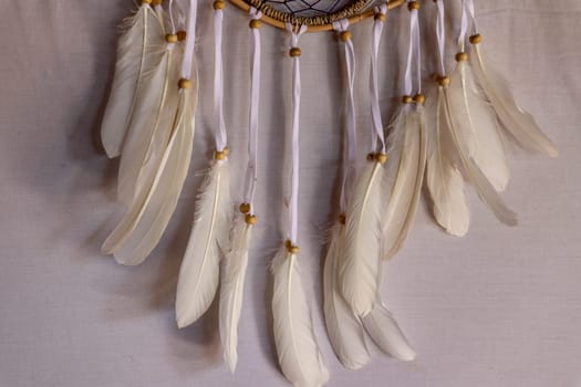 Closeup of white dream catcher a small white hoop decorated with feathers and beads.