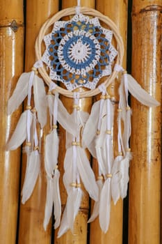 Blue Dreamcatcher with feathers and beads isolated on a wodden background.