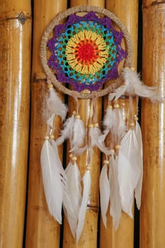 Beautiful multicolored handmade dreamcatcher on natural bamboo background.