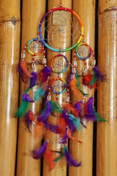 Beautiful multicolored handmade dreamcatcher on natural bamboo background.