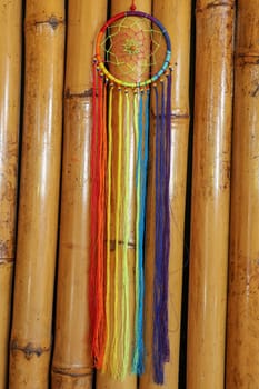 Beautiful multicolored handmade dreamcatcher on natural bamboo background.
