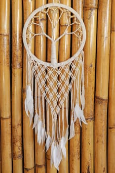White dreamcatcher - Indian amulet that protects the sleeper from evil spirits and diseases.. The tree - symbol of life. Dream catcher on bamboo background.