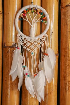 White dreamcatcher - Indian amulet that protects the sleeper from evil spirits and diseases.. The tree - symbol of life. Dream catcher on bamboo background.