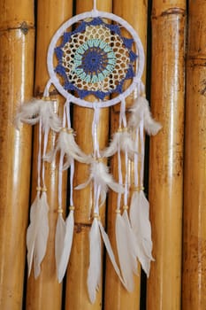 Blue Dreamcatcher with feathers and beads isolated on a wodden background.