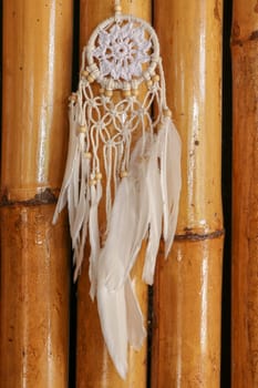 Dream catcher, decorated with white feathers and wooden beads, on a wooden surface. Dream catcher with wooden circle. Knitted Native American amulet with the symbol of Yin Yang on a wodden background.