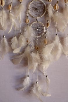 Closeup of white dream catcher a small white hoop decorated with feathers and beads.