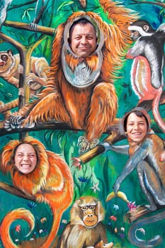 ZOOLOGICAL GARDEN, TARGU MURES COUNTY, ROMANIA - APRIL.16.2015: People from a socially disadvantaged community on a zoological garden, zoo, taking a fun souvenir picture through the holes of a panel painted with monkeys