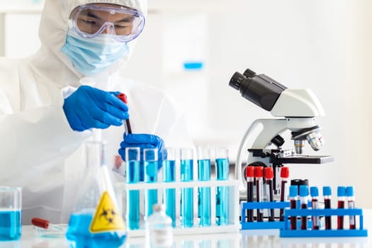 Scientists hold blood sample test tube and examine for his research and develop vaccine for coronavirus covid-19 pandemic. Medical Science and technology concept.