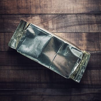 Blank aluminium foil package on vintage wood table background. Coffee packaging mockup. Top view. Flat lay.