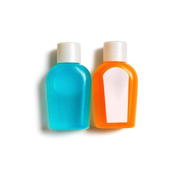 Two blank cosmetics shampoo bottles on white paper background. Set of toiletries. Top view. Flat lay.