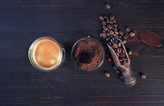 Coffee espresso cup, roasted coffee beans and ground powder on vintage wooden background. Top view. Flat lay.