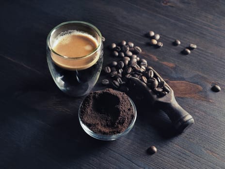 Espresso on wood kitchen table background. Coffee cup, roasted coffee beans and ground powder.