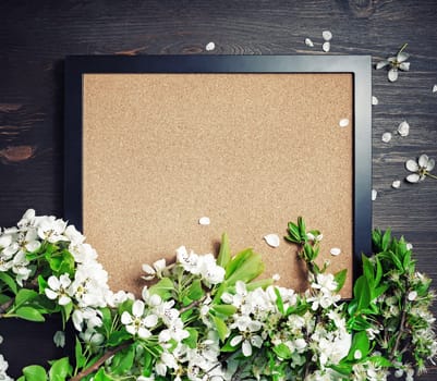Blank photo frame with spring flowers on wooden background. Responsive design template. Top view. Flat lay.