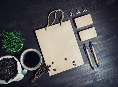 Photo of blank kraft paper stationery set and coffee on vintage wooden background. Template for placing your design. Top view. Flat lay.