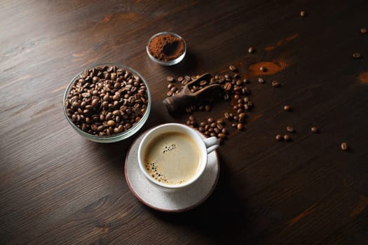 Coffee cup, coffee beans and ground powder on kitchen table background.