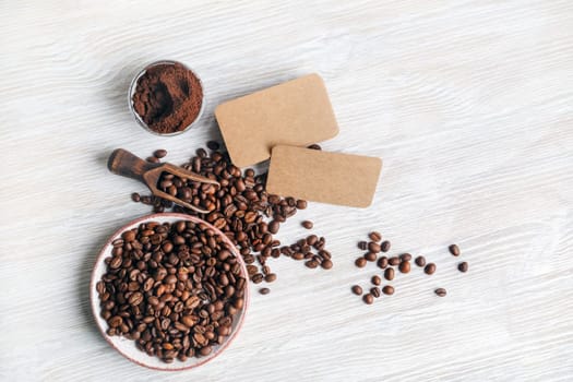 Coffee beans, blank kraft business cards and coffee ground on light wood table background. Top view. Flat lay.