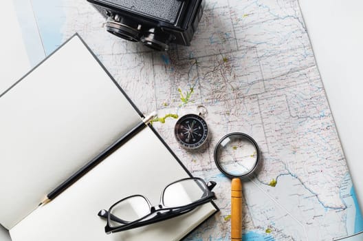 Planning vacation trip with map, compass, notepad, magnifier, glasses, pencil and camera. Travel or vacation concept. Flat lay.