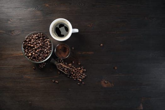 Vintage coffee background. Coffee cup, roasted coffee beans and ground powder on wood kitchen table.. Flat lay.