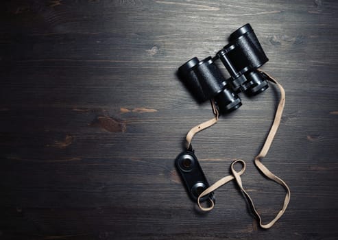 Photo of black vintage binocular on wooden background. Top view. Flat lay.