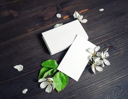 Photo of blank white business cards and flowers on wooden background. Branding ID template.